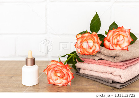 Spa composition with towels, flowers and facial serum on the wooden boards. 133112722
