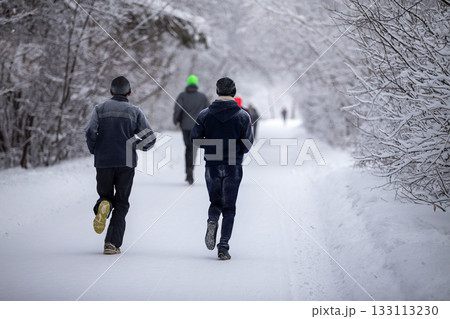 Rear view group of runners running winter marathon in park Rear view group of runners running winter marathon in park 133113230