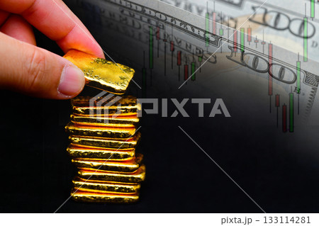 Hand holding a gold bars the candlestick chart and us dollar background , Fluctuations in gold prices concept. Hand holding a gold bars the candlestick chart and us dollar background , Fluctuations in gold prices concept. 133114281