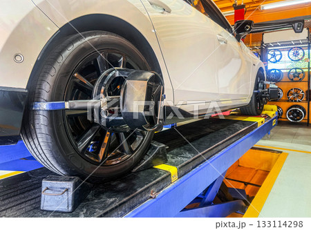 Car wheel alignment on stand with sensors check in service station. Vehicle inside garage workshop for auto camber fixing work, Vehicle inside garage workshop. Car wheel alignment on stand with sensors check in service station. Vehicle inside garage workshop for auto camber fixing work, Vehicle inside garage workshop. 133114298