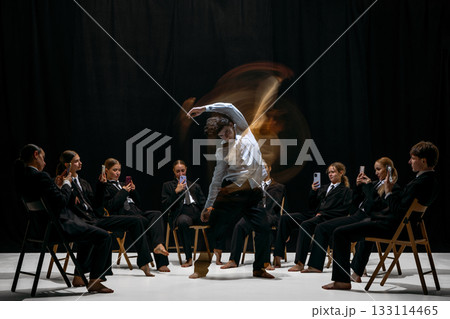 Performer blurred motion surrounded by individuals recording with smartphones symbolizing digital attention culture 133114465