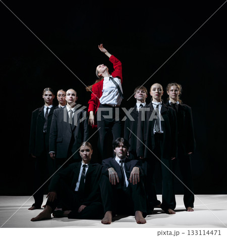 Leader in red coat standing above team symbolizing visionary direction and disruptive startup energy 133114471