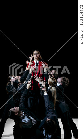 Leader in red coat elevated above group as symbolic model for leadership training and team education 133114472