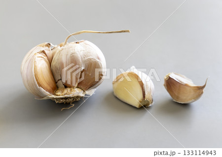 Fresh garlic on a grey background, whole bulb and cloves, closeup. Food ingredient Fresh garlic on a grey background, whole bulb and cloves, closeup. Food ingredient 133114943