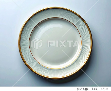 Elegant table setting. Ceramic plate with a classic white and gold design on a white background. Porcelain kitchenware. Close-up. Top view. 133116306