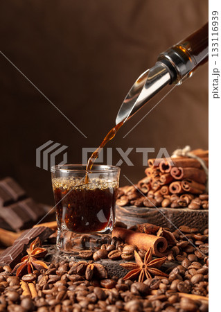 Coffee liquor is poured into a glass. Coffee liquor is poured into a glass. 133116939