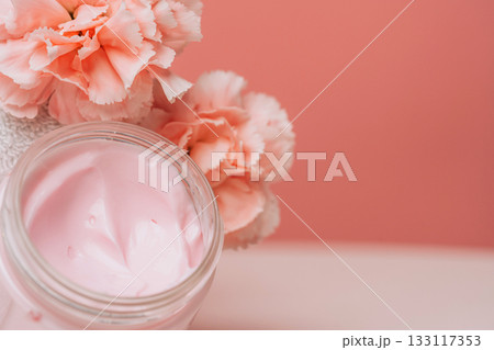 Open pink cream jar with soft carnations 133117353