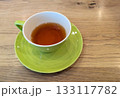 木製テーブルの上に置かれたライムグリーンのカップソーサーと紅茶 133117782