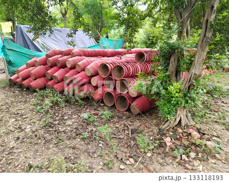 Stacks of red painted clay flower pots arranged in large quantity outdoors at a nursery garden, traditional earthen terracotta planters for plantation and decoration purposes in bulk storage Stacks of red painted clay flower pots arranged in large quantity outdoors at a nursery garden, traditional earthen terracotta planters for plantation and decoration purposes in bulk storage 133118193