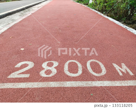 Red jogging track with "2800 M" distance marker in park, synthetic running lane with clear milestone for fitness enthusiasts, promoting outdoor exercise and healthy lifestyle 133118205