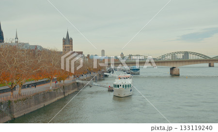 Beautiful autumn scene with boat cruising along river near historic city bridge 133119240