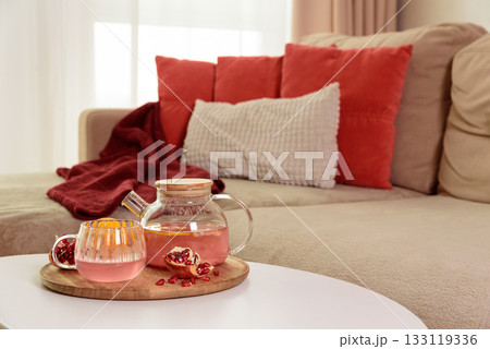Glass Teapot and Teacup with Pomegranate Drink with Ginger and Citrus on Cozy Sofa with Autumn Decor Glass Teapot and Teacup with Pomegranate Drink with Ginger and Citrus on Cozy Sofa with Autumn Decor 133119336