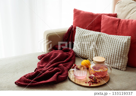 Glass Teapot and Teacup with Pomegranate Drink with Ginger and Citrus on Cozy Sofa with Autumn Decor Glass Teapot and Teacup with Pomegranate Drink with Ginger and Citrus on Cozy Sofa with Autumn Decor 133119337
