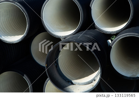 The black drainage pipes are neatly stacked, showcasing smooth interior surfaces and industrial textures, highlighting building materials and engineering design. High quality photo 133119565