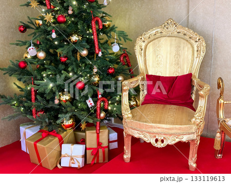 Santas golden chair near decorated Christmas tree Santas golden chair near decorated Christmas tree 133119613
