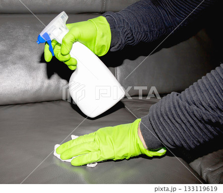 A man wearing cleaning gloves wipes the leather sofa. A man wearing cleaning gloves wipes the leather sofa. 133119619