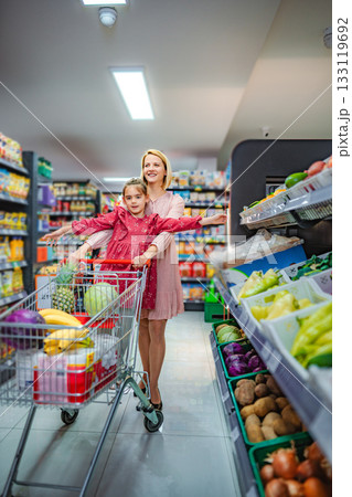 Mother and daughter having fun while grocery shopping in supermarket 133119692