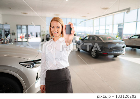 Woman holding new car key in showroom Woman holding new car key in showroom 133120202