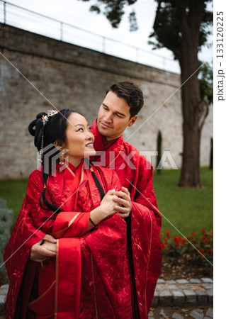 Interracial wedding couple embracing wearing traditional Chinese attire Interracial wedding couple embracing wearing traditional Chinese attire 133120225