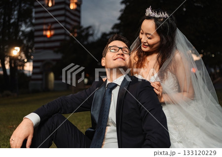 Interracial couple celebrating wedding in park during evening 133120229