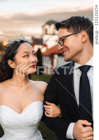 Interracial couple celebrating wedding day looking at each other 133120234