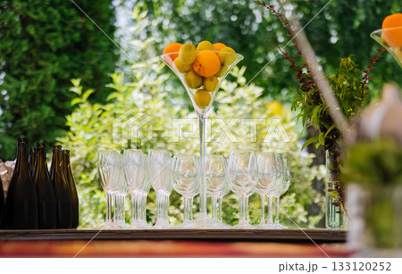 Garden bar setup with citrus centerpiece, champagne flutes, and bottles ready to serve Garden bar setup with citrus centerpiece, champagne flutes, and bottles ready to serve 133120252