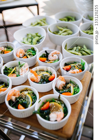 Mini shrimp seaweed salads in white bowls on a catering tray at an outdoor event Mini shrimp seaweed salads in white bowls on a catering tray at an outdoor event 133120255