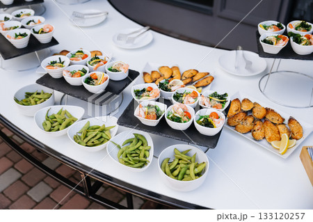 Catering spread with edamame, shrimp salads, and baked mussels on elegant display 133120257