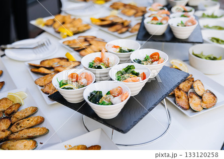 Catering buffet with edamame bowls, shrimp salads, and baked mussels outdoors Catering buffet with edamame bowls, shrimp salads, and baked mussels outdoors 133120258