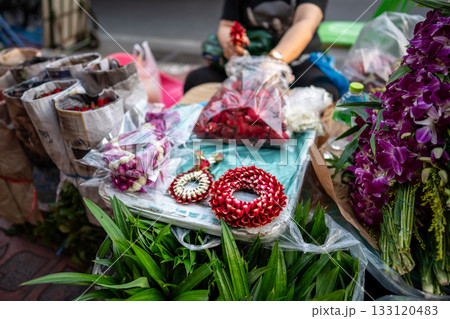 Local street market stall with vendor assembling and selling ceremonial flower wreaths for customers Local street market stall with vendor assembling and selling ceremonial flower wreaths for customers 133120483