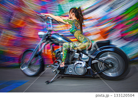 Vibrant motion body painted woman on a custom motorcycle. A woman with intricate body paint poses on a custom motorcycle. Swirl bokeh. Vibrant motion body painted woman on a custom motorcycle. A woman with intricate body paint poses on a custom motorcycle. Swirl bokeh. 133120504