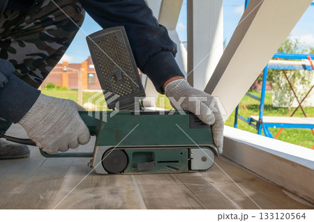 Caucasian male adult using belt sander for outdoor deck construction 133120564