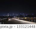 A nighttime view of Warsaw skyline captured from a modern footbridge, with shining skyscrapers and the Palace of Culture glowing in the distance. 133121448