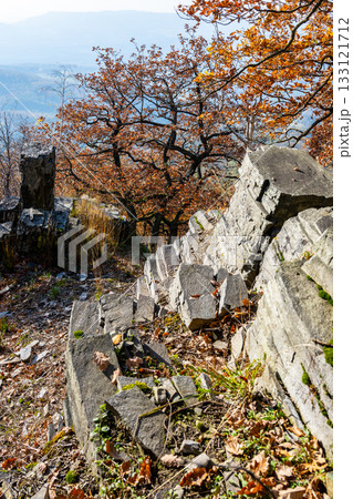 On a sunny autumn day, the landscape at Sedlo Mountain features vibrant foliage and rocky terrain, inviting exploration. The warmth of the sun enhances the beauty of the natural surroundings. 133121712