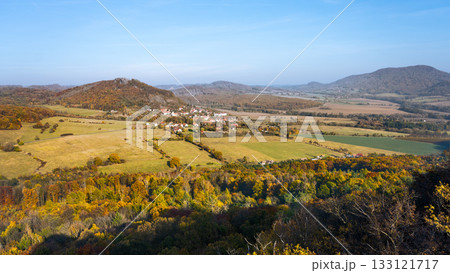 A stunning autumn view from Trojhora in the Central Bohemian Uplands, showcasing colorful foliage over sprawling fields and distant hills under a clear blue sky. A stunning autumn view from Trojhora in the Central Bohemian Uplands, showcasing colorful foliage over sprawling fields and distant hills under a clear blue sky. 133121717