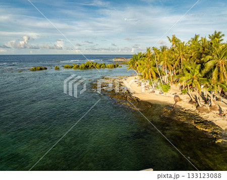 Tropical sandy beach with tall palm trees and rocky shoreline meeting the sea. Siargao, Philippines. Tropical sandy beach with tall palm trees and rocky shoreline meeting the sea. Siargao, Philippines. 133123088