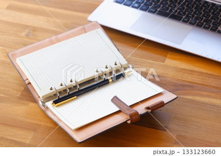 リング式のシステム手帳を開いてデスクワークをしているイメージ 133123660
