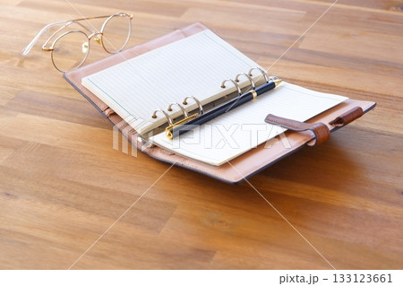 リング式のシステム手帳を開いてデスクワークをしているイメージ 133123661