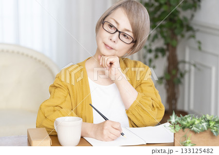 リビングでエンディングノートを書くシニア女性 133125482