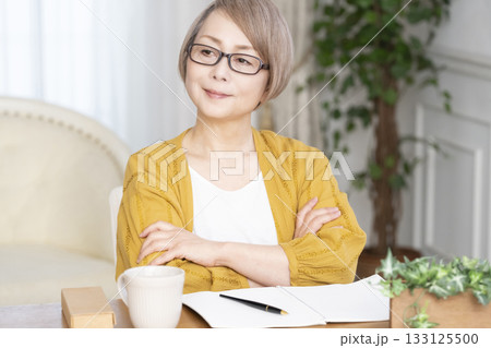 リビングでエンディングノートを書くシニア女性 133125500