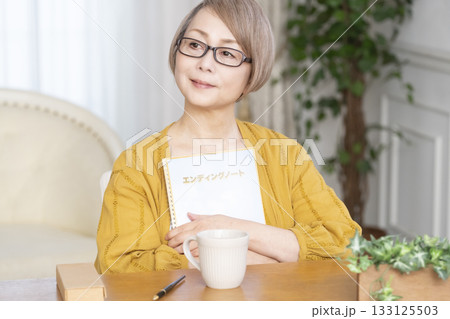 リビングでエンディングノートを書くシニア女性 133125503