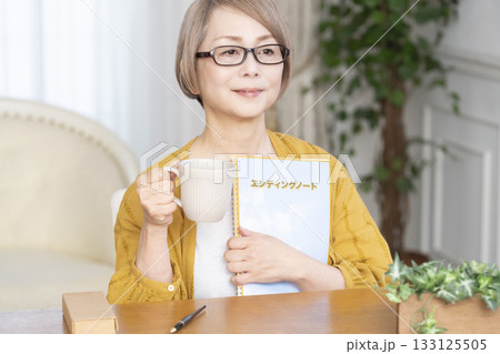 リビングでエンディングノートを書くシニア女性 リビングでエンディングノートを書くシニア女性 133125505