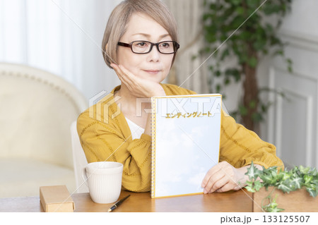 リビングでエンディングノートを書くシニア女性 133125507