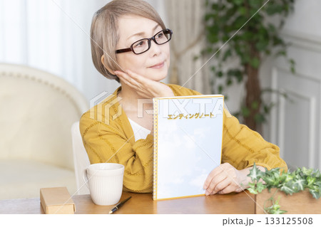 リビングでエンディングノートを書くシニア女性 133125508