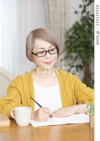 リビングでエンディングノートを書くシニア女性 133125510