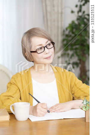リビングでエンディングノートを書くシニア女性 133125511
