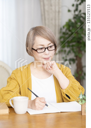 リビングでエンディングノートを書くシニア女性 133125513