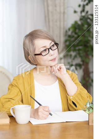 リビングでエンディングノートを書くシニア女性 133125514