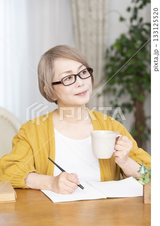 リビングでエンディングノートを書くシニア女性 133125520