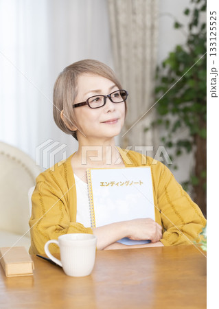 リビングでエンディングノートを書くシニア女性 133125525